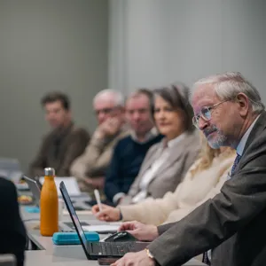 En gruppe mennesker som sitter ved et bord og ser på en bærbar PC