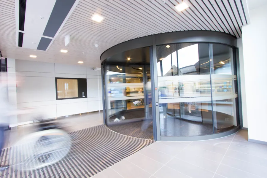 Et rom med glassvegger med glassdør og flisegulv