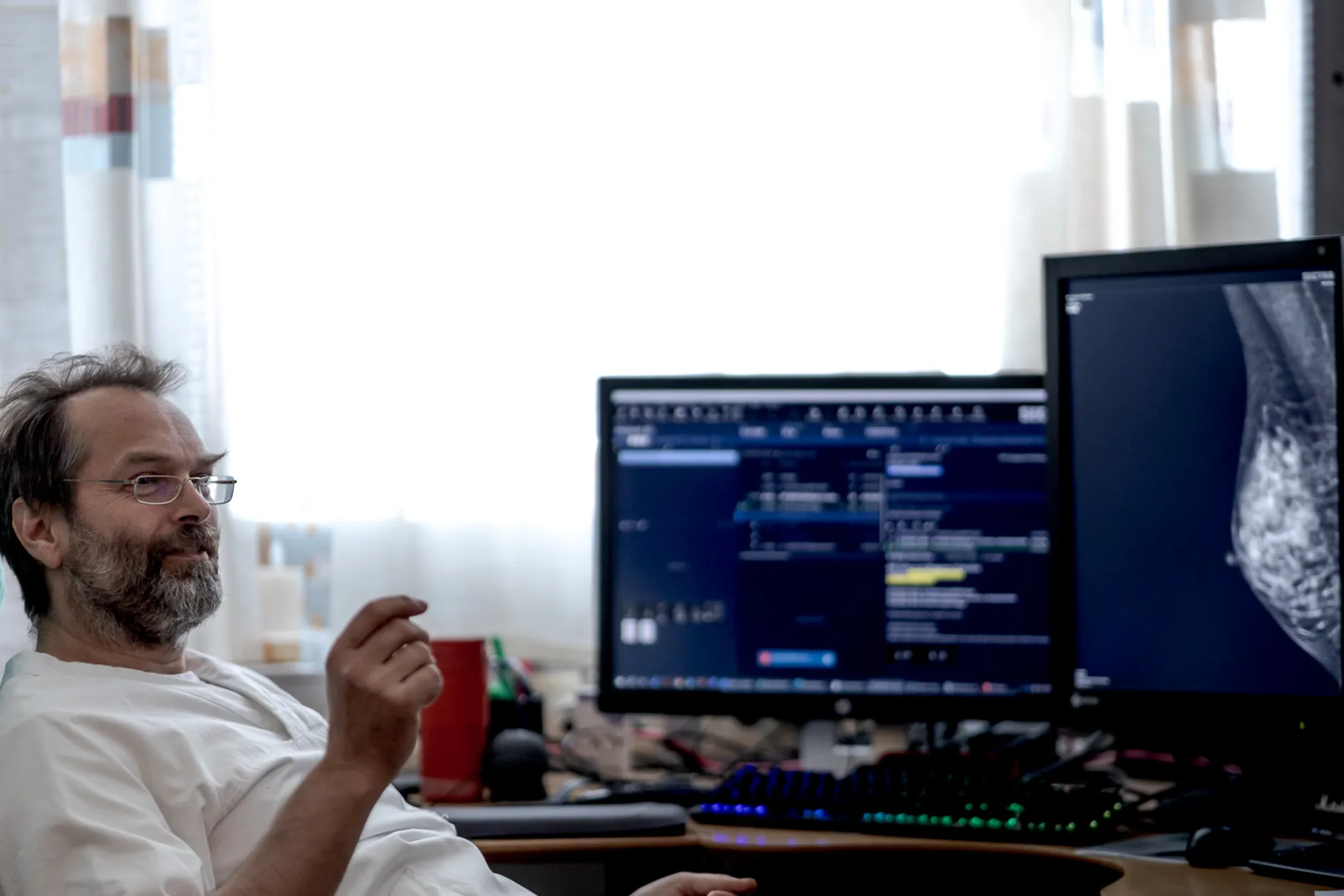 En mann som sitter ved et skrivebord med et par dataskjermer