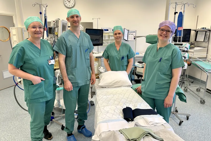 En gruppe mennesker i kirurgiske scrubs som står ved siden av en pasient