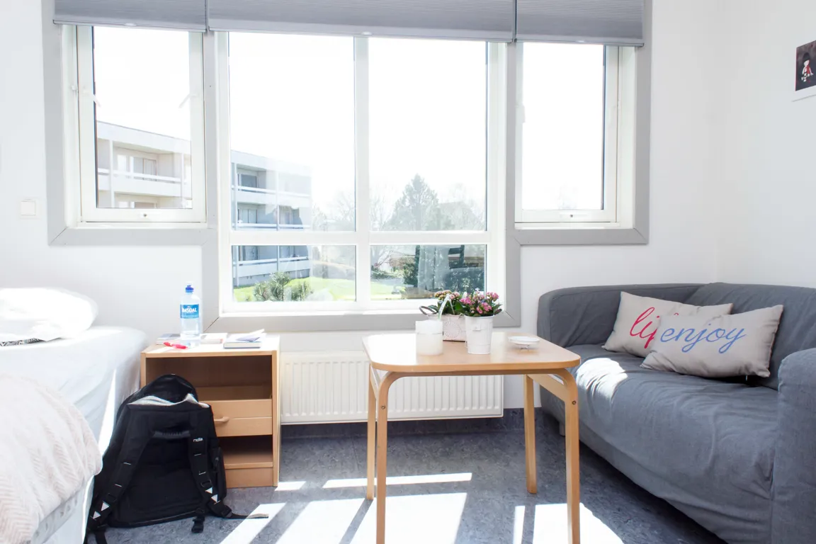 Et rom med en seng og et bord med vindu